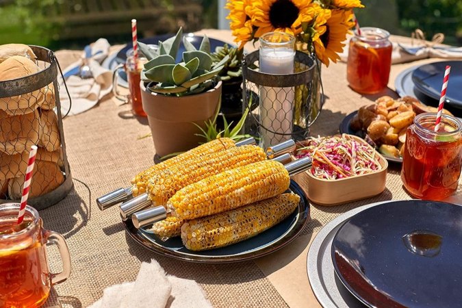 Outdoor table set with dishes, iced tea, corn, and rolls