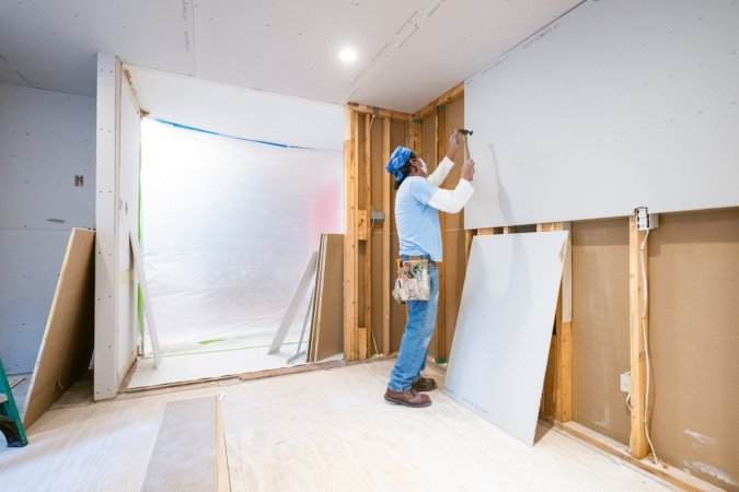 A DIYer installing drywall in a home basement with bathroom.