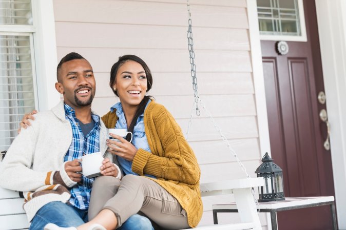 A young couple chatting with neighbors on the front porch.