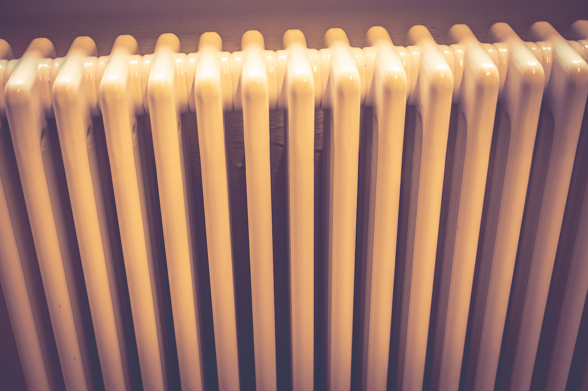 Close up image of a retro radiator with fins in dappled sunlight.